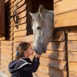 Dziewczynka obejmuje konia w wiejskiej stajni, budując z nim więź